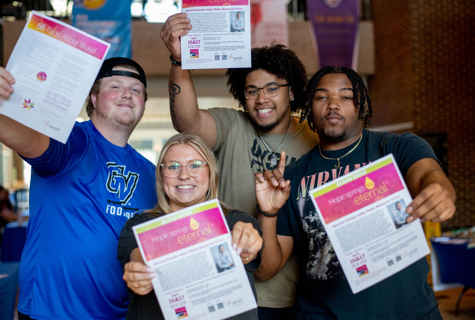 Students smiling for the camera and holding up posters promoting the Jaden Blake Memorial Blood Drive